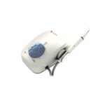 Ablatore dentale UDS-K, bianco con quadrante di controllo blu e manipolo collegato.