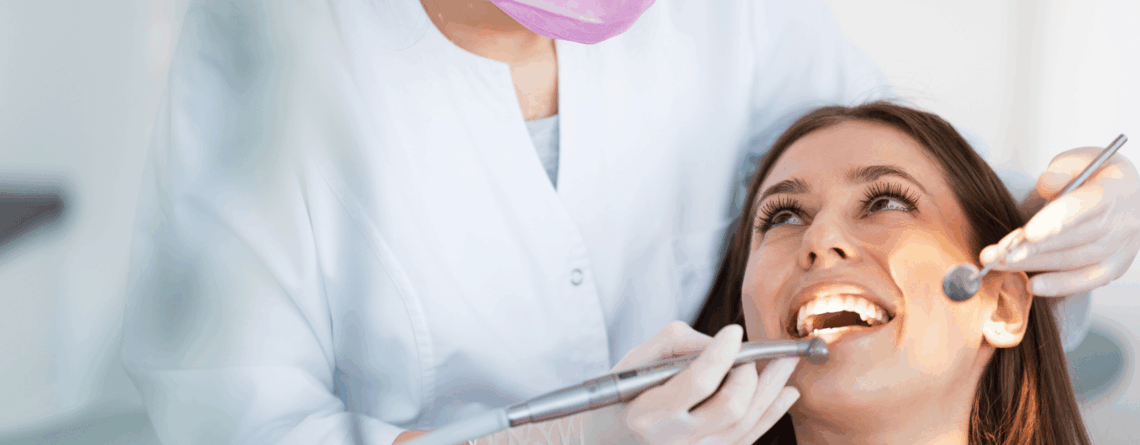 Dentista che esamina i denti di una donna sorridente per attrarre pazienti studio dentistico.
