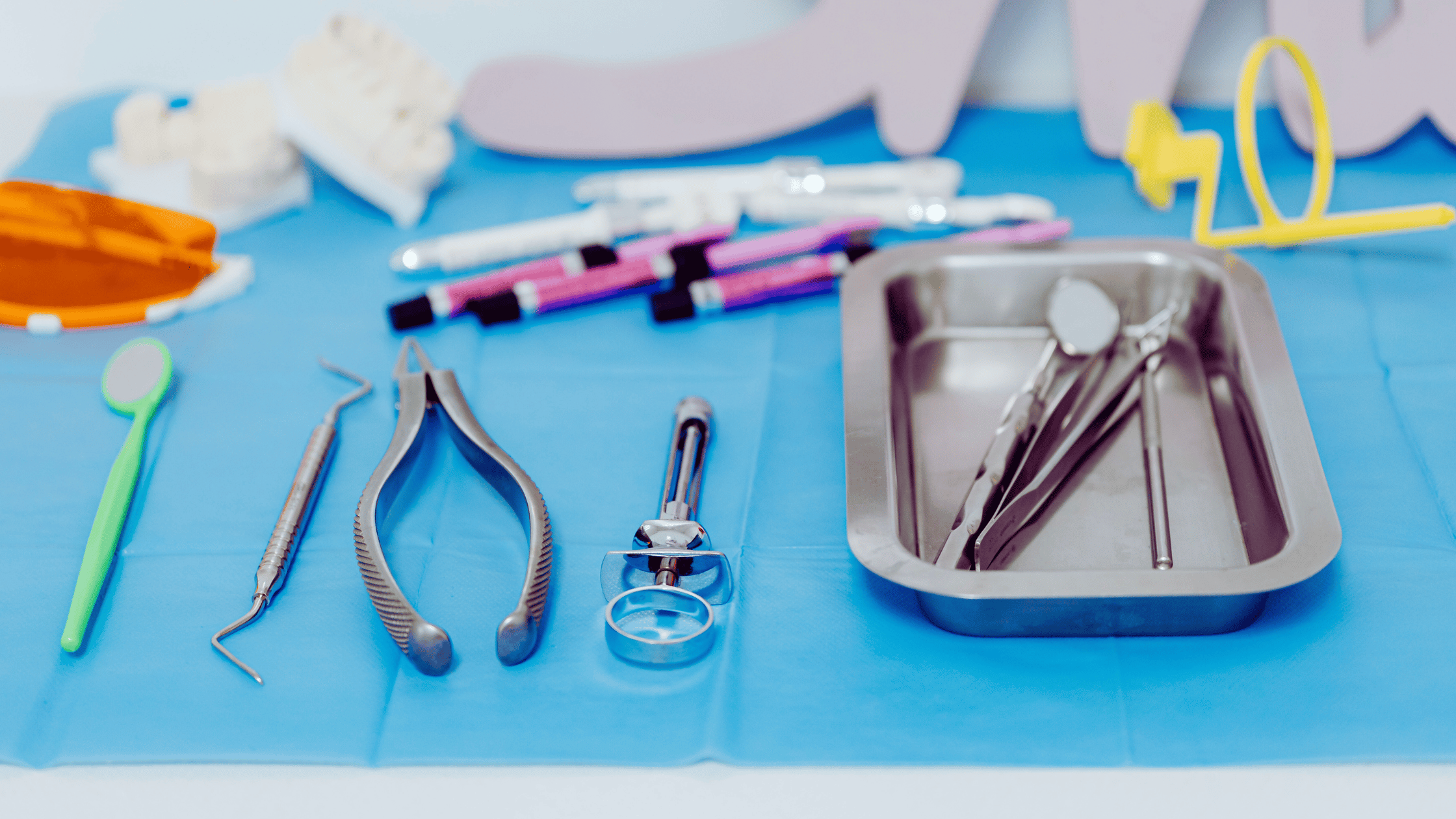 Vari strumenti dentistici e attrezzi sono disposti su una superficie sterile blu.